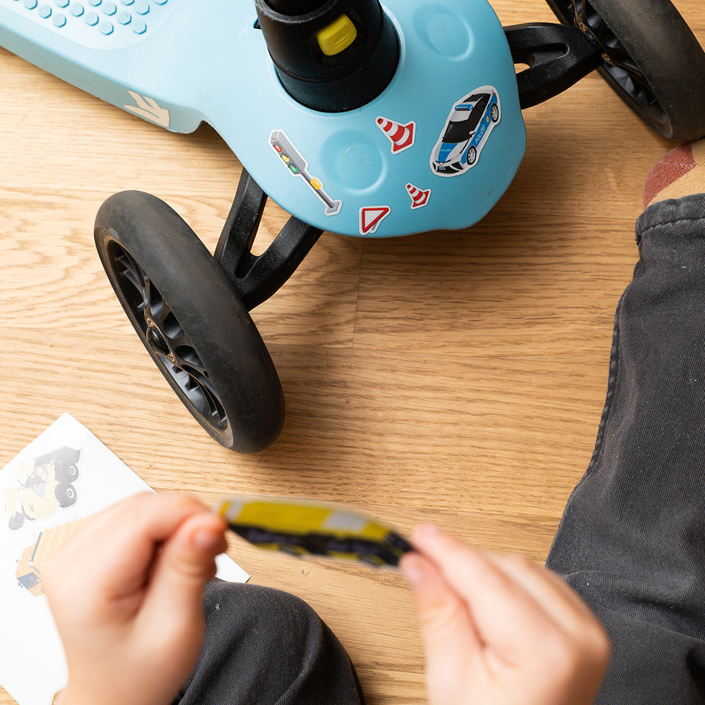 Applying reflective bus on kids scooter with wooden floor and hands