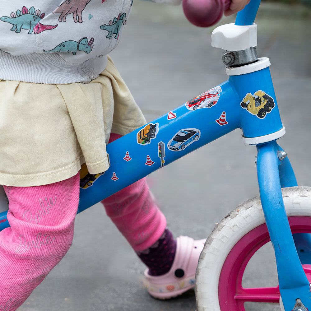 Kid riding his pushbike with car reflective stickers on frame, in daylight