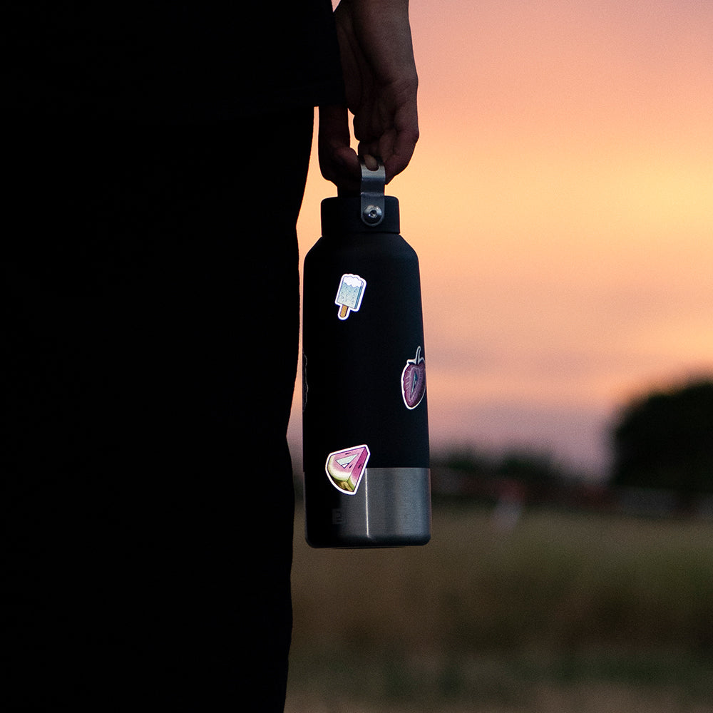 Hand holding a water bottle with reflective stickers.