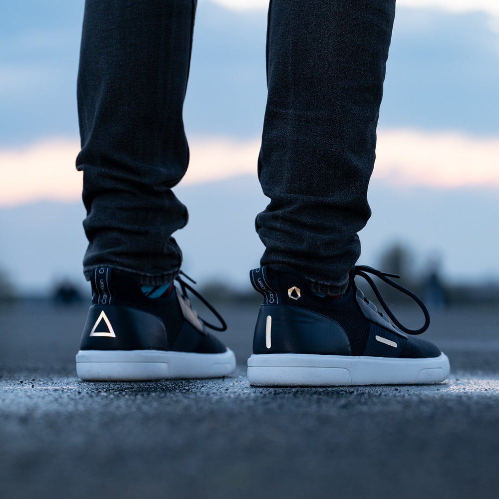 Schuhe auf Asphalt mit Himmel im Hintergrund, mit reflektierenden Aufklebern